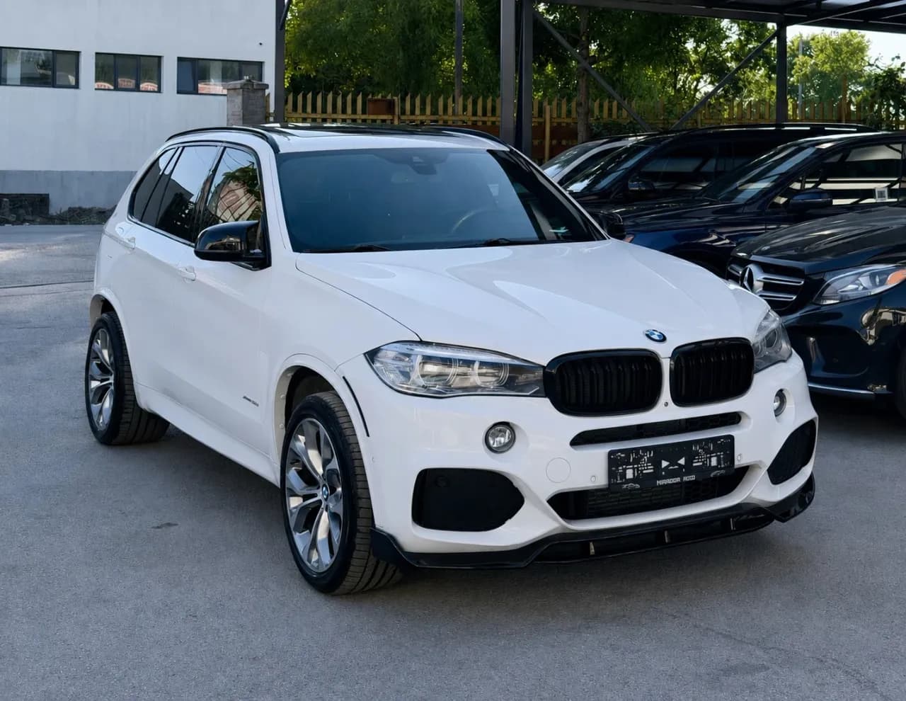 White BMW X5 F15 xDrive35i with M Sport package and black grille, front three-quarter view