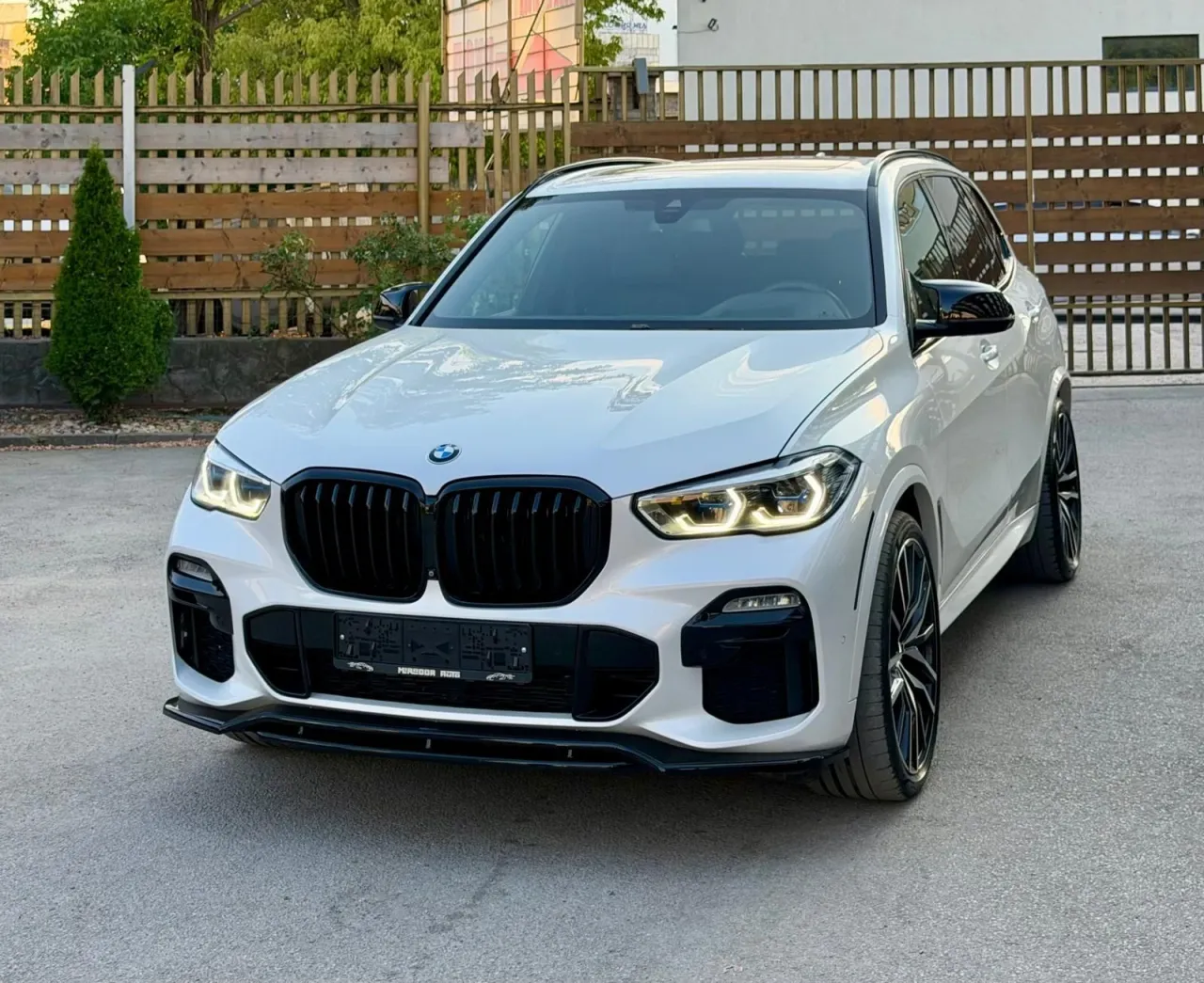 BMW X5 G05 xDrive40i в бял перлен цвят, изглед отпред с черна решетка и включени лазерни фарове